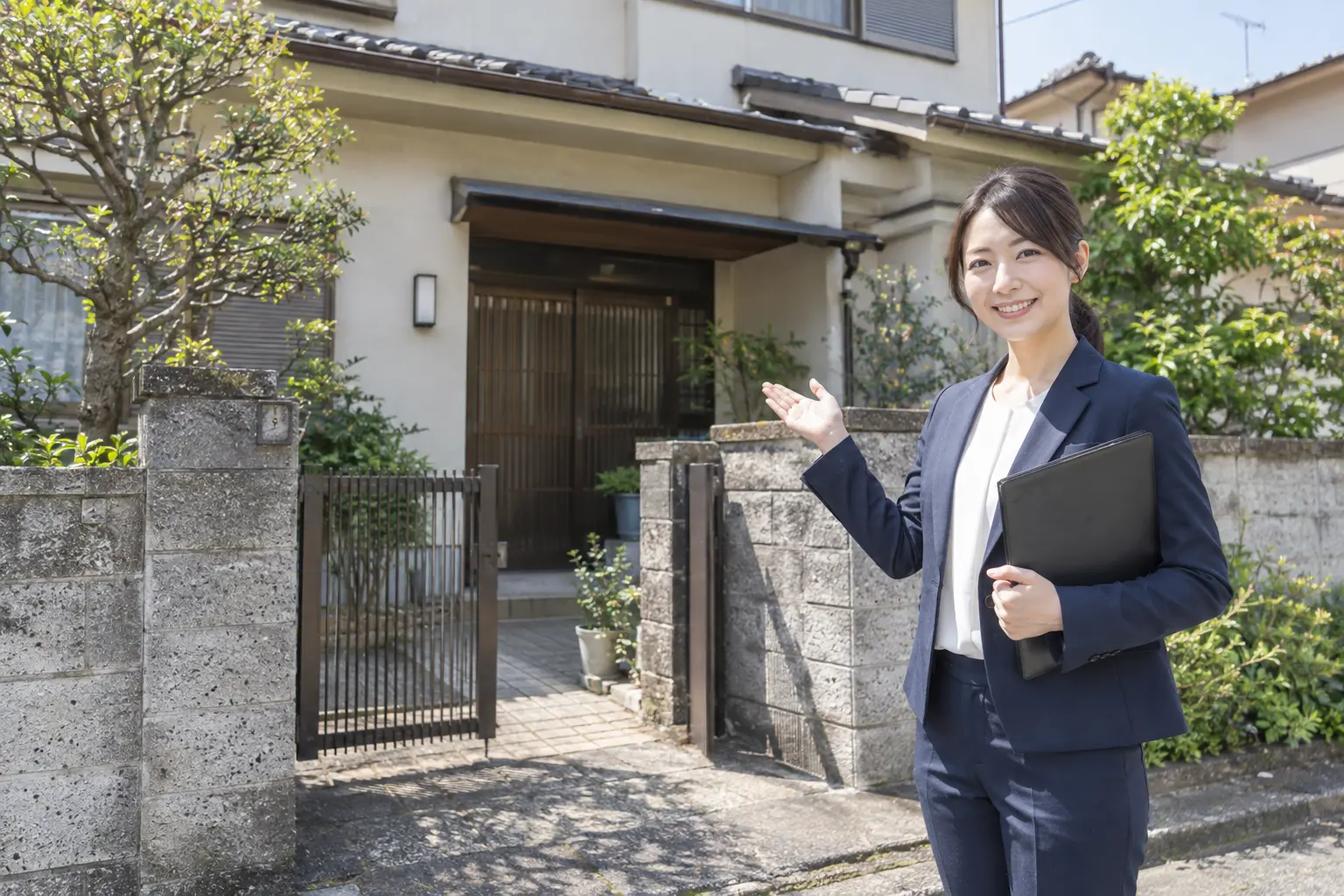 空き家の前で相談者をご案内する女性担当者のイメージ